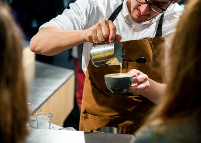 Photo of a barista pouring milk into a coffee